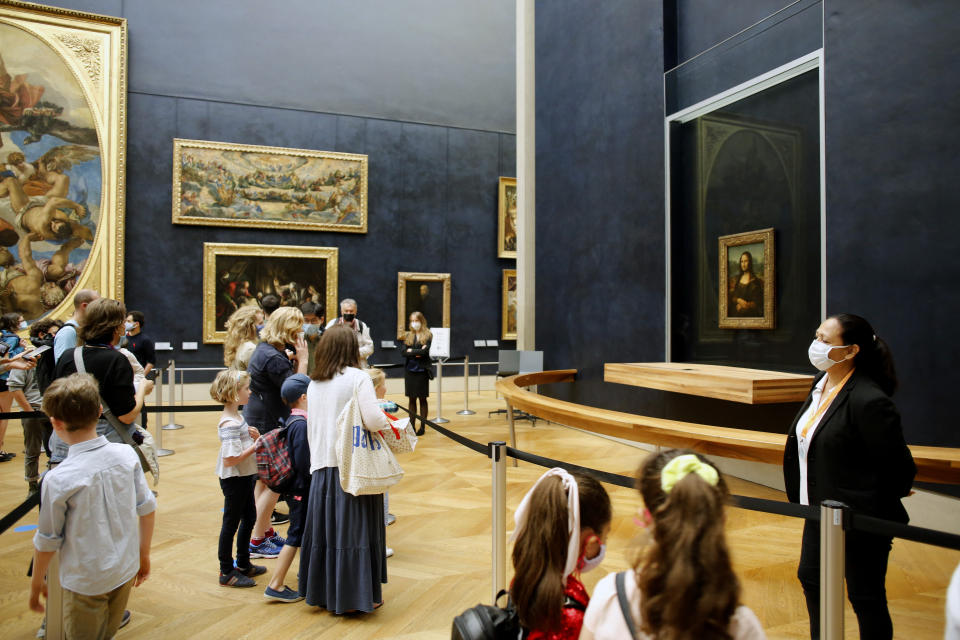 Visitors watch the Leonardo da Vinci's painting Mona Lisa, in Paris, Monday, July 6, 2020. The home of the world's most famous portrait, the Louvre Museum in Paris, reopened Monday after a four-month coronavirus lockdown. (AP Photo/ Thibault Camus)