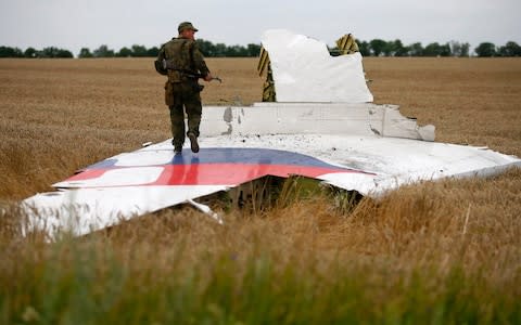 A separatist fighter stands on wreckage of the airliner near the village of Grabovo in July 2014 - Credit: MAXIM ZMEYEV/Reuters