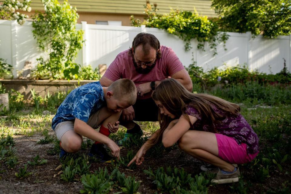 Josh Mitchell and his kids Owen, 9, and Zoey, 7, look for grasshoppers at their home in Midvale on Tuesday, May 30, 2023. | Spenser Heaps, Deseret News