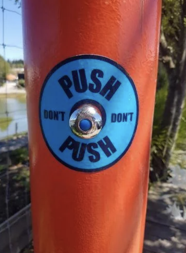 Circular button on a pole with contradictory instructions "PUSH DON'T PUSH."