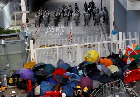 Anti-extradition bill protesters use umbrellas to build a barricade while riot police stand guard on the Legislative Council compound during the anniversary of Hong Kong's handover to China in Hong Kong