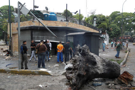 People look at the damage in the entrance of a bakery, after it was looted in Caracas, Venezuela April 20, 2017. REUTERS/Christian Veron