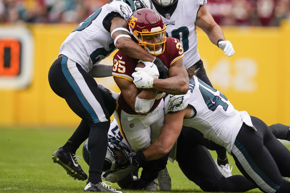 Washington Football Team running back Jonathan Williams (35) is tackled by Philadelphia Eagles safety Rodney McLeod (23) middle linebacker T.J. Edwards (57) and outside linebacker Alex Singleton (49) during the first half of an NFL football game, Sunday, Jan. 2, 2022, in Landover, Md. (AP Photo/Al Drago)