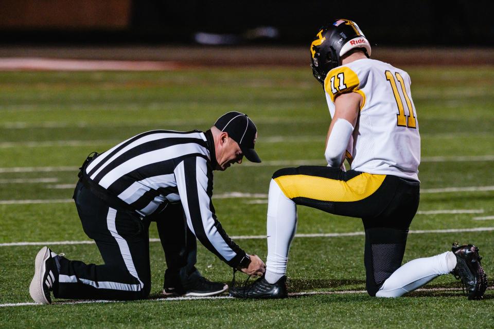 A referee ties the shoe of Nothmor's Ashton Clark, 11, during a week 13 division 6 high school football playoff game, Friday, Nov. 3 at Bulldog Stadium in Heath, Ohio.