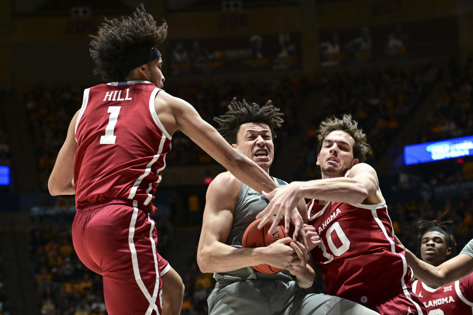 West Virginia forward James Okonkwo (32) protects a rebound from Oklahoma forward Jalen Hill (1) and Oklahoma guard Jake Moser (30) during the second half of an NCAA college basketball game in Morgantown, W.Va., Saturday, Feb. 4, 2023. (AP Photo/William Wotring)