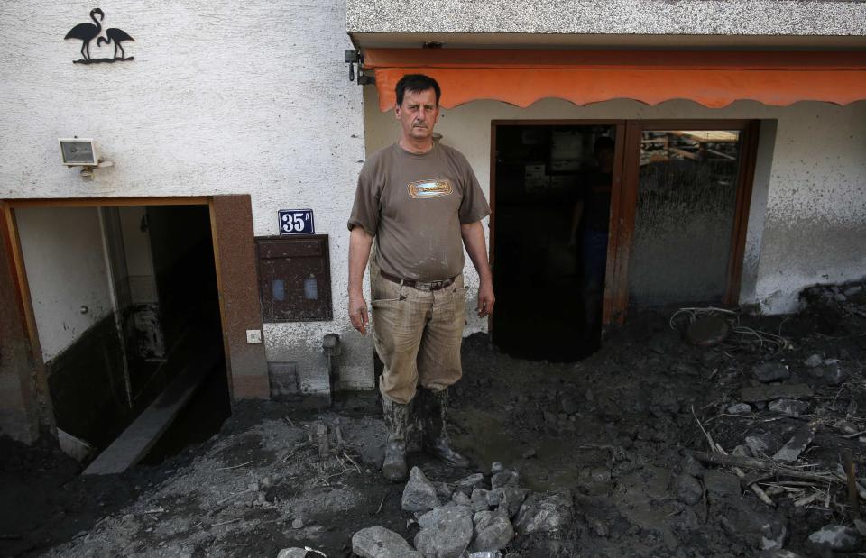 Vahid Neslanovic, poses in front of his flood-damaged house in Topcic Polje