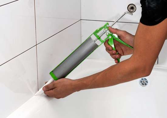  close up of man caulking bathroom tiles