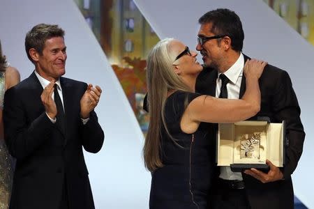 Jury President Jane Campion (C) kisses director Nuri Bilge Ceylan (R), Palme d'Or award winner for his film "Winter Sleep", as jury member actor Willem Dafoe applauds during the closing ceremony of the 67th Cannes Film Festival in Cannes May 24, 2014. REUTERS/Eric Gaillard