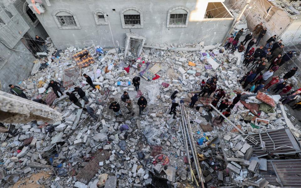 Palestinians inspect the site of an Israeli strike on a house