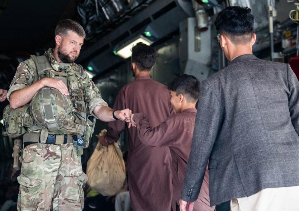 Handout photo issued by the Ministry of Defence (MoD) of a member of the UK Armed Forces fist-bumping a child evacuee at Kabul airport (LPhot Ben Shread/MoD) (PA Media)