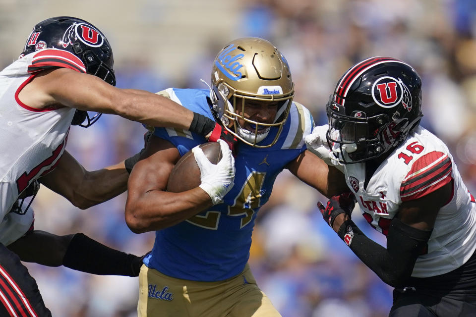 UCLA running back Zach Charbonnet (24) is tackled by Utah safety R.J. Hubert (11) and cornerback Zemaiah Vaughn (16) during the first half of an NCAA college football game in Pasadena, Calif., Saturday, Oct. 8, 2022. (AP Photo/Ashley Landis)