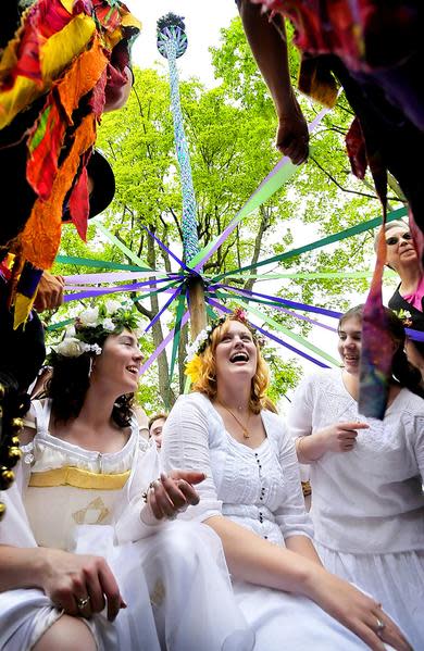 Young women dressed in all white group together at the base of the maypole at Shepherd University's McMurran Hall during a May Day celebration in Shepherdstown, W.Va.