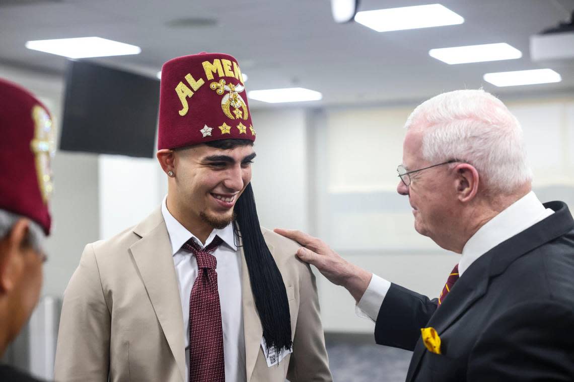 Brayan Solano, left, a former patient at the Shriners Children’s hospital in Tampa, gets a Shriners hat put on him during a press conference at Jackson Memorial Hospital on Friday, July 22, 2022. Jackson Health System, University of Miami Health and Shriners Children’s are partnering to open a new pediatric orthopedic center at Jackson.