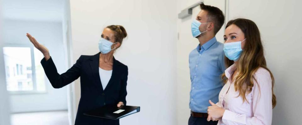 Happy Couple Buying New Home With Realtor Wearing Face Masks