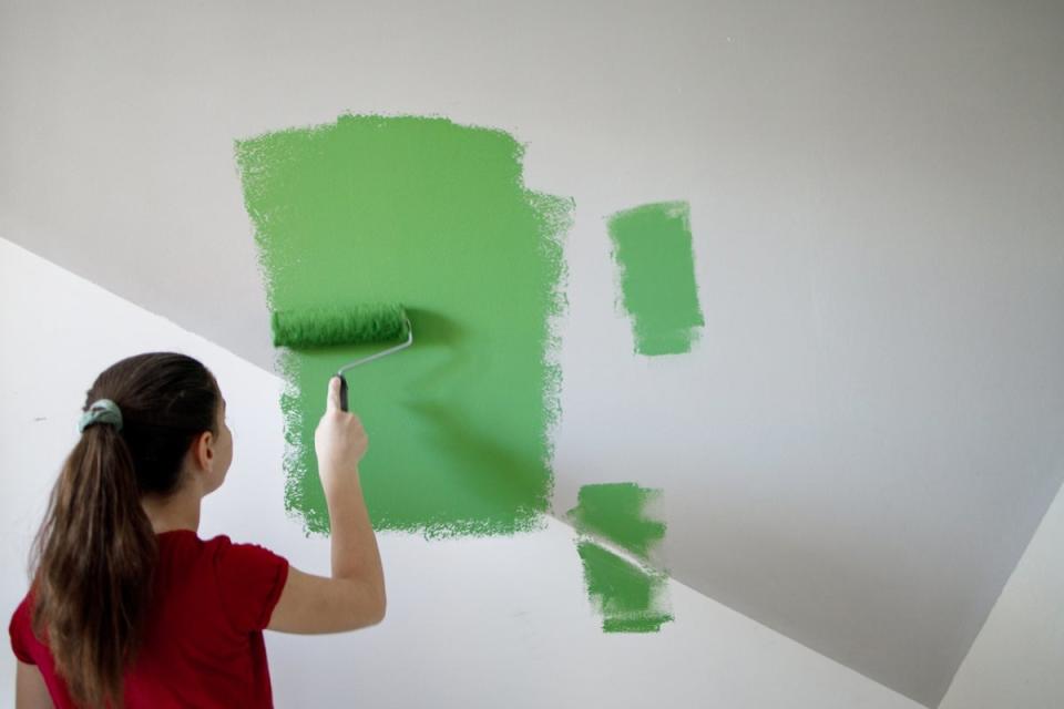 Girl painting a wall green