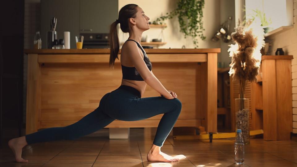 Woman doing yoga in kitchen with sunshine coming through the window in winter