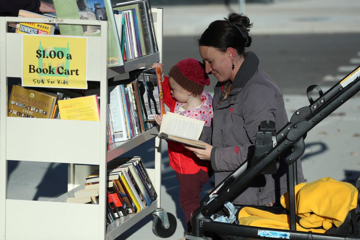 Amanda Blake and her daughter Ginny 2, from Detroit, look over the book cart in front of Next Chapter Books on East Warren Ave. Thursday, Nov 09, 2023.