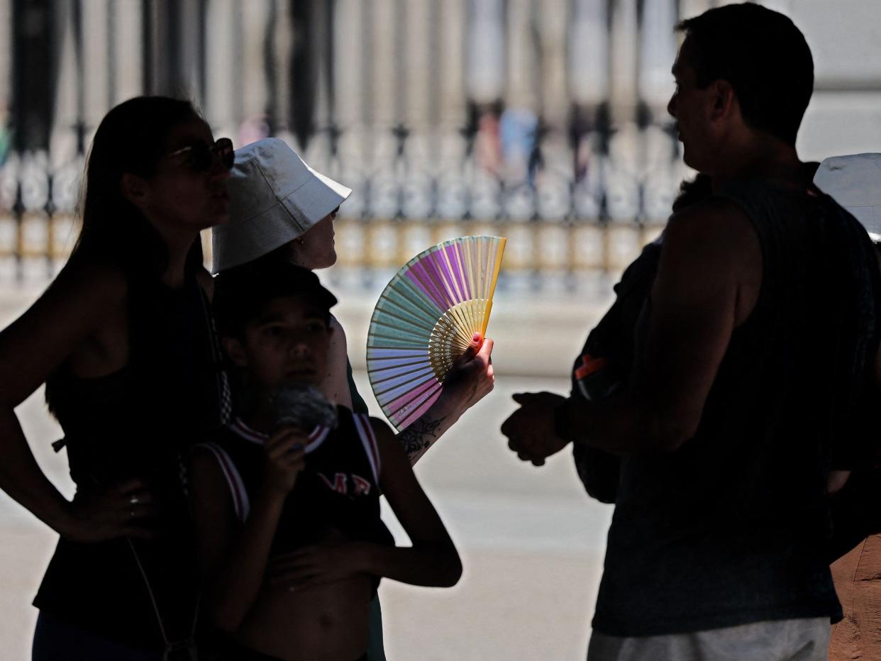 Tourists protect themselves from the sun as they are visiting the Royal Palace in Madrid (Thomas Coex /AFP via Getty Images)