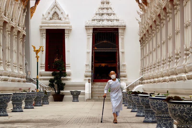 A buddhist nun wearing a face masks walks at Wat Mahathat Yuwaratrangsarit temple in Bangkok