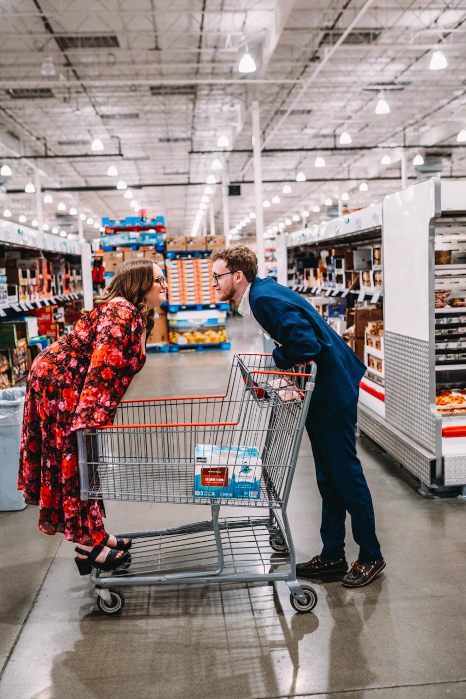 A couple look at each other as they lean over opposite sides of a shopping cart.