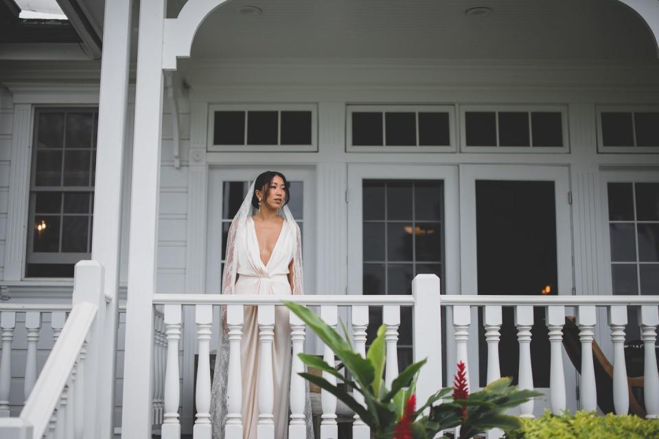 a person in a white dress stands on a porch