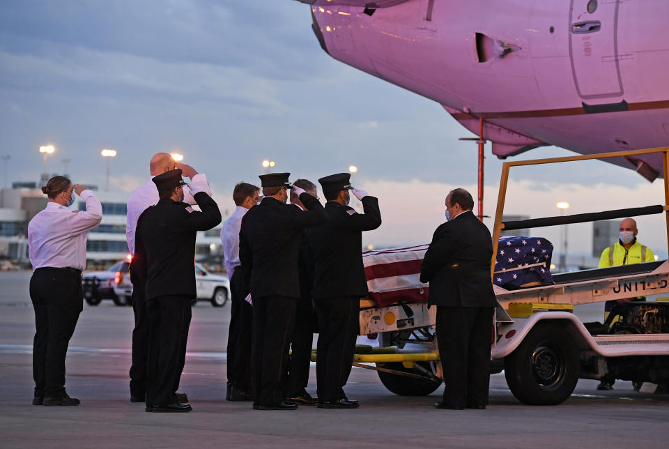 Ambulnz paramedics and Aurora firefighters salute as the casket carrying the body of paramedic Paul Cary is removed from a plane at Denver International Airport on Sunday, May 3, 2020, in Denver. Cary died from coronavirus after volunteering to help combat the pandemic in New York City. (Helen H. Richardson/The Denver Post via AP, Pool)