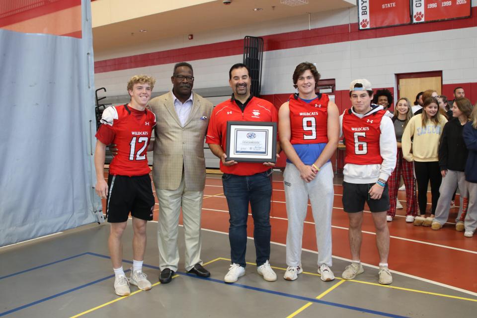 Milton High football coach Steve Dembowski poses with former New England Patriot linebacker Andre Tippett, now the team’s Executive Director of Community Affairs, after being selected as the New England Patriots High School Coach of the Week. Also shown are Milton players Owen McHugh (No. 12), K.J. Beckett (No. 9) and Jack Finnegan (No. 6).