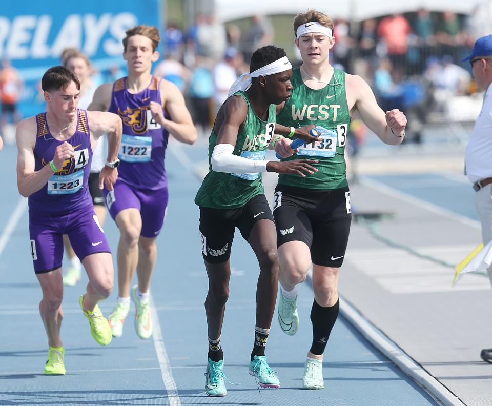 Iowa City West's Aidan Jacobsen exchanges the baton to teammate Moustafa Tiea during the boys' distance medley relay in the Drake Relays at Drake Stadium on Friday, April 28, 2023, in Des Moines, Iowa.