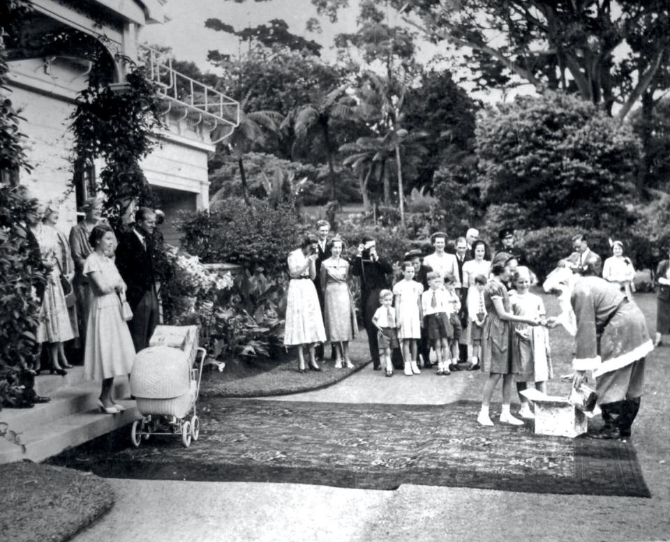 <p>While in New Zealand, Queen Elizabeth and Prince Philip watch from the steps of the Government House as Santa gives out presents.</p>