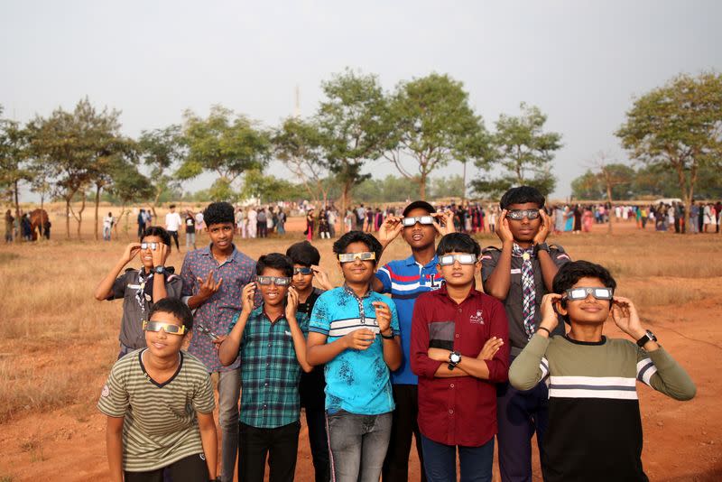 Boys use solar viewers to watch the annular solar eclipse in Cheruvathur