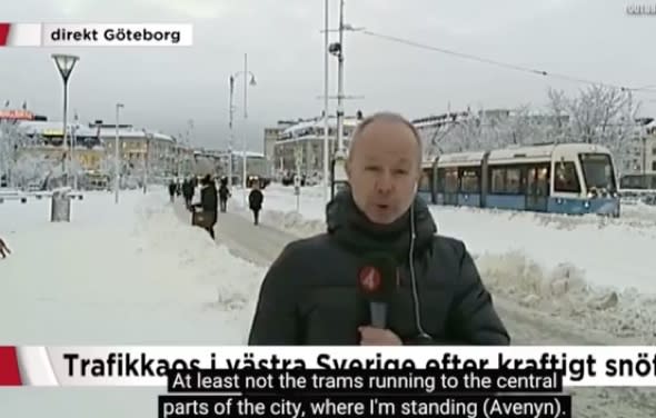 Reporter says snow halted trams as one goes past behind him