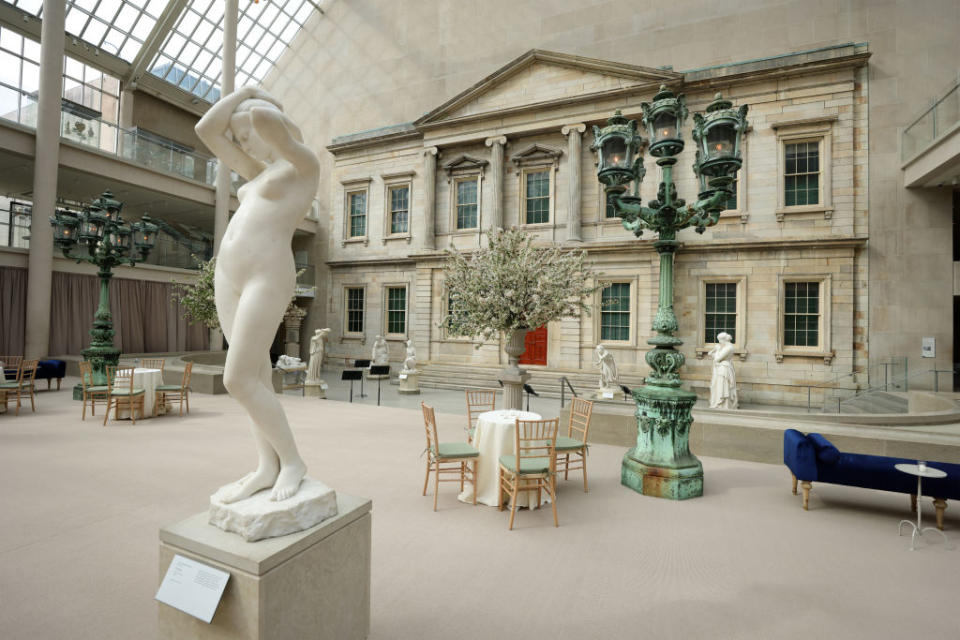 Interior of a sculpture gallery with classical statues on plinths, tables, and chairs arranged for an event