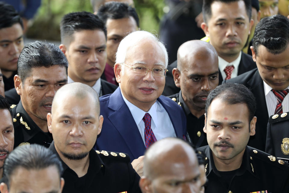 FILE - In this July 4, 2018, file photo, former Malaysian Prime Minister Najib Razak, center, arrives at a court house in Kuala Lumpur, Malaysia. Najib is hardly lying low ahead of his corruption trial set to begin Tuesday, Feb. 12, 2019, on charges related to the multibillion-dollar looting of the 1MDB state investment fund. He’s crooned about slander in an R&B video and vilified the current government on social media to counter portrayals of him as corrupt and out of touch. Najib denies wrongdoing and his lawyers are seeking delay.(AP Photo/Vincent Thian, File)