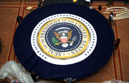 Workers spin a carpet with the presidential seal into place at the site of the Commander in Chief inaugural ball for President-elect Donald Trump in Washington, D.C. January 19, 2016. REUTERS/Rick Wilking