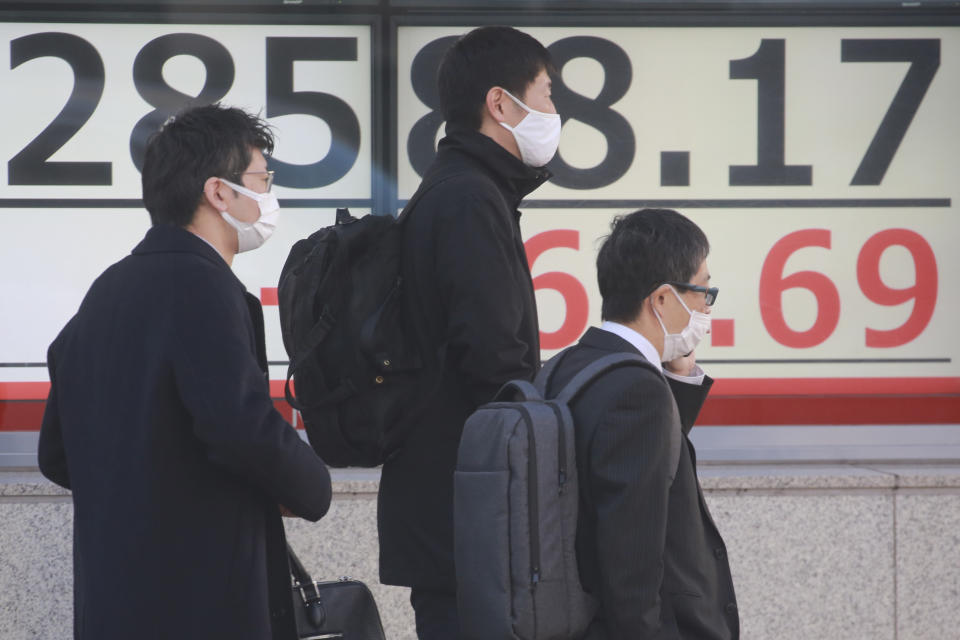 People walk by an electronic stock board of a securities firm in Tokyo, Wednesday, Jan. 12, 2022. Asian stock markets followed Wall Street higher on Wednesday after Federal Reserve chairman Jerome Powell said monetary policy would return to normal and interest rates might be raised earlier than planned.(AP Photo/Koji Sasahara)