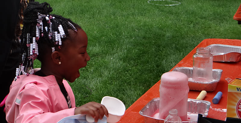 Jazlyn Anderson, 4, reacts with surprise as her “volcano” of baking soda and vinegar erupts during a Cleveland school district science demonstration at a community festival. (Patrick O’Donnell)