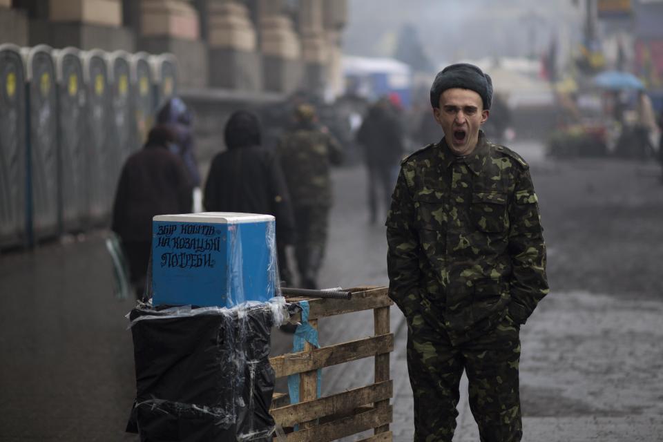 A Ukrainian man wearing camouflage uniform yawns as he asks for donations to support the Ukrainian military with the slogan on box reading "collecting money for Cossacks' needs", at Kiev's Independence Square, Ukraine, Tuesday, March 4, 2014. Vladimir Putin ordered tens of thousands of Russian troops participating in military exercises near Ukraine's border to return to their bases as U.S. Secretary of State John Kerry was on his way to Kiev. Tensions remained high in the strategic Ukrainian peninsula of Crimea as troops loyal to Moscow fired warning shots to ward off protesting Ukrainian soldiers. Cossacks were originally a 14th century military force predominantly living in Ukraine and southern Russia. (AP Photo/Emilio Morenatti)