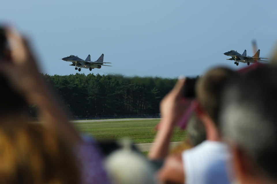 FILE - Visitors watch as Slovak Air Force MiG-29s fly over an airport during an airshow in Malacky, Slovakia, Saturday, Aug. 27, 2022. Former Soviet satellite Slovakia has been a NATO member since 2004, but the reality of belonging to the world’s biggest military alliance really kicked in after Russia’s invasion of Ukraine a year ago. The small central European country now hosts thousands of NATO troops while allied aircraft patrol its skies. (AP Photo/Petr David Josek, File)