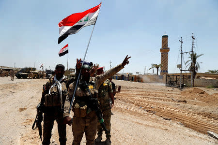 Iraqi security forces gesture in the town of Garma, Iraq, May 26, 2016.REUTERS/Thaier Al-Sudani