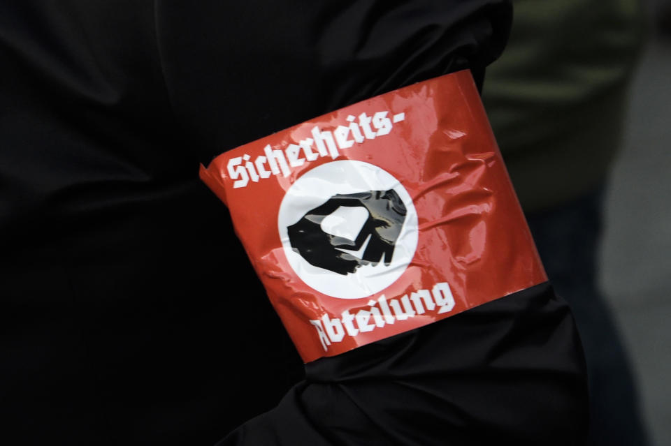A demonstrator with an armband reading 'Security Department' attends a protest against the visit of German Chancellor Angela Merkel at the East German city Chemnitz on Friday, Nov. 16, 2018. (AP Photo/Jens Meyer)