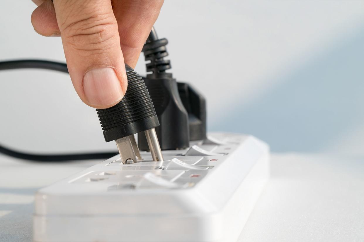 close up elderly hand plugging into electrical outlet