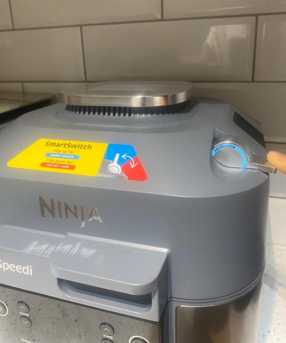 Christina Chrysostomou, an olive-skinned woman using finger to demonstrate how to use the SmartSwitch on a Ninja Speedi Rapid Cooker