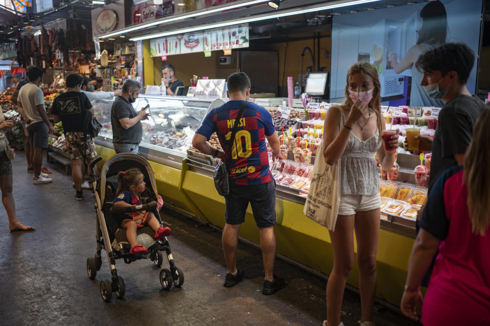 Un individuo con una camiseta del delantero del Barcelona Lionel Messi compra fruta en el marcado de la La Boquería en el centro de Barcelona, el jueves 1 de julio de 2021. (AP Foto/Joan Mateu)