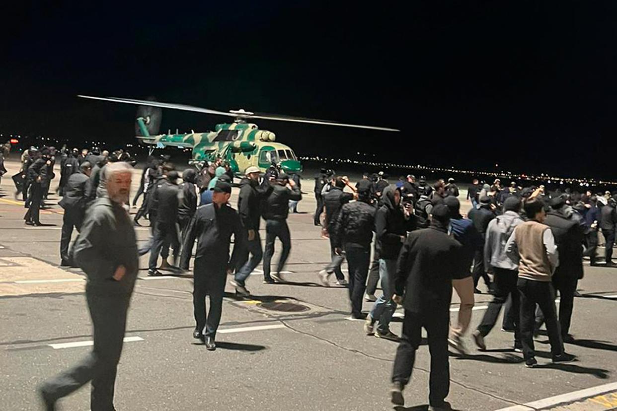 People in the crowd walk shouting antisemitic slogans at an airfield of the airport in Makhachkala, Russia, on Monday (AP)