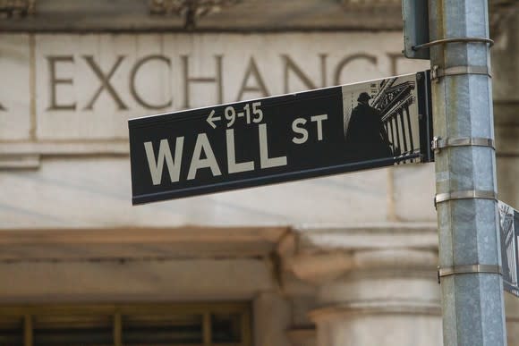 Wall Street sign with Exchange sign on a stone wall in background