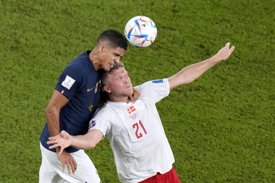 France's Raphael Varane, and Denmark's Andreas Cornelius, go for a header during the World Cup group D soccer match between France and Denmark, at the Stadium 974 in Doha, Qatar, Saturday, Nov. 26, 2022. (AP Photo/Alessandra Tarantino)