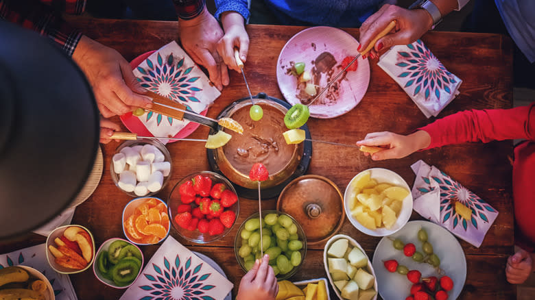 Hands around a fondue pot