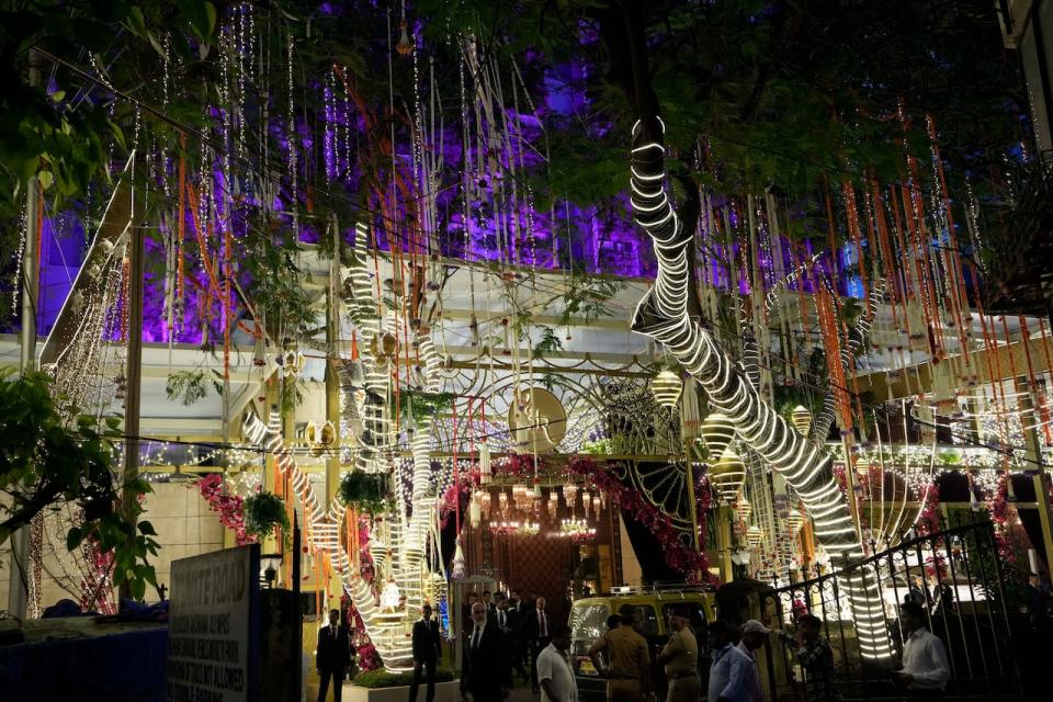 People walk past the Antilia mansion, house of billionaire Mukesh Ambani, while it is lit up ahead of his son Anant Ambani and Radhika Merchant's wedding in Mumbai, India, Wednesday. 