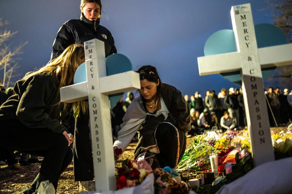 People sign a heart on a cross in memory of one of the people killed during a vigil at the Rock on the Michigan State University campus in East Lansing on Wednesday, Feb. 15, 2023, to honor and remember the victims of the mass shooting that happened on the MSU campus that left three dead and five others injured.