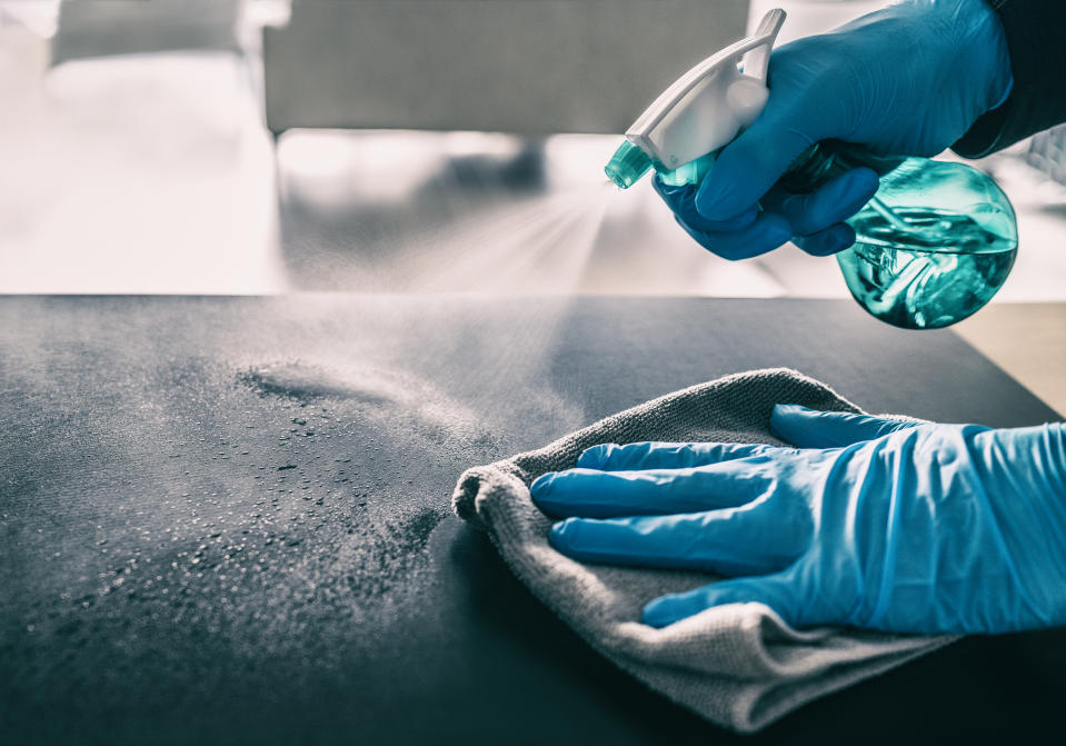 Surface sanitizing against COVID-19 outbreak. Home cleaning spraying antibacterial spray bottle disinfecting against coronavirus wearing nitrile gloves. Sanitize hospital surfaces prevention.